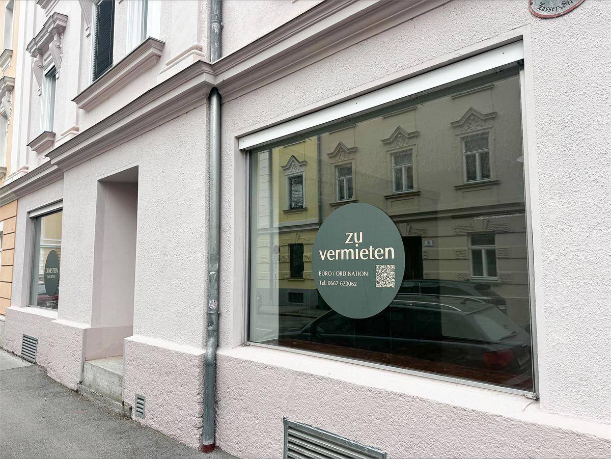 Seitenansicht der Ladenfront mit großem Schaufenster und 'zu vermieten' Schild, das die Verfügbarkeit anzeigt.