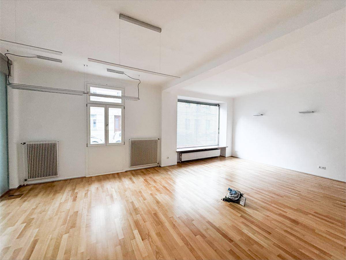 Kleinerer, heller Raum mit Holzfußboden, weißen Wänden und einem Fenster, ideal als Einzelbüro oder Arbeitszimmer.