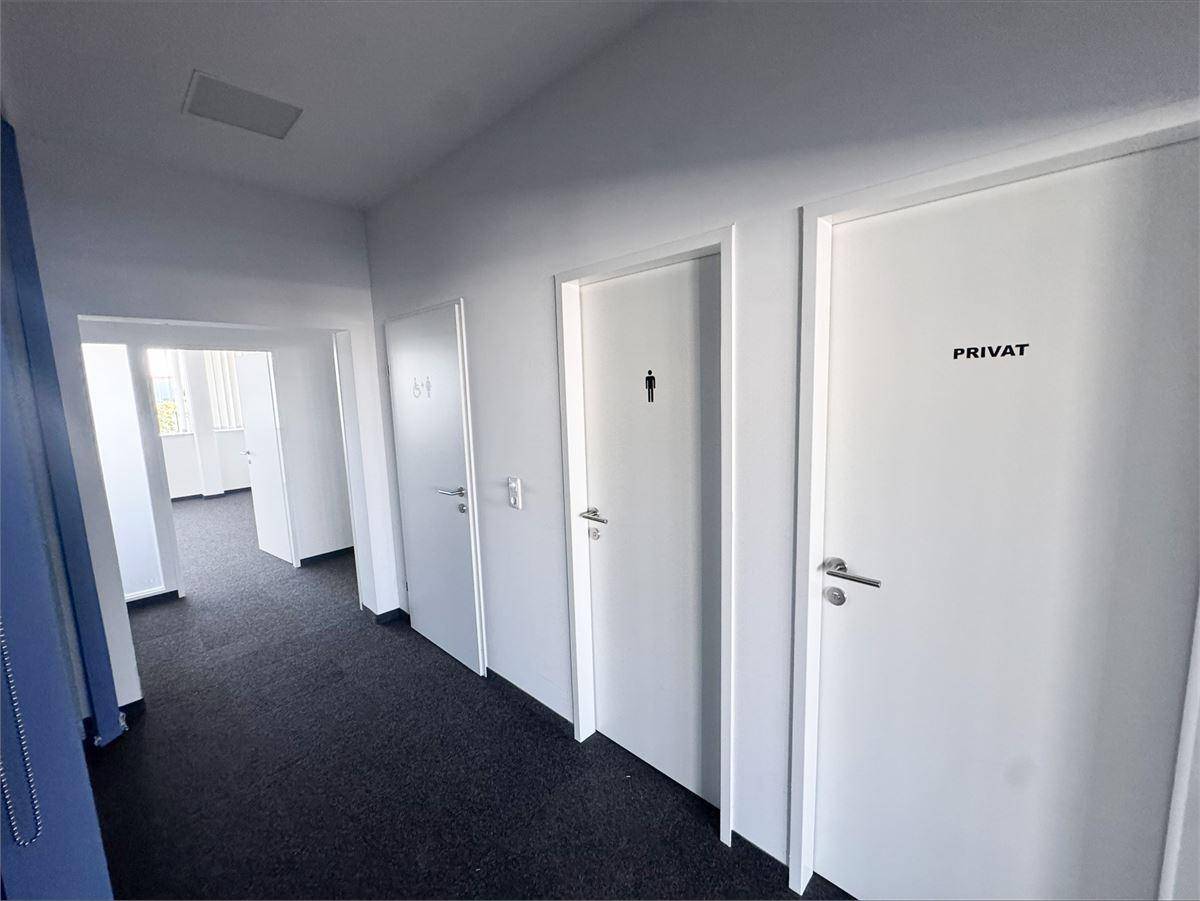 Flur mit mehreren Türen, darunter Toiletten und ein privater Raum, mit Teppichboden.