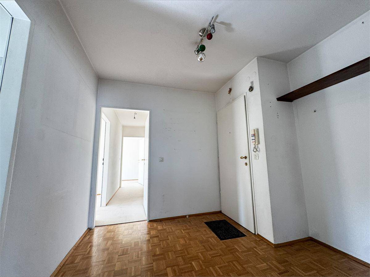 Eingangsbereich mit Parkettboden, weiß gestrichenen Wänden und Zugang zu weiteren Räumen.