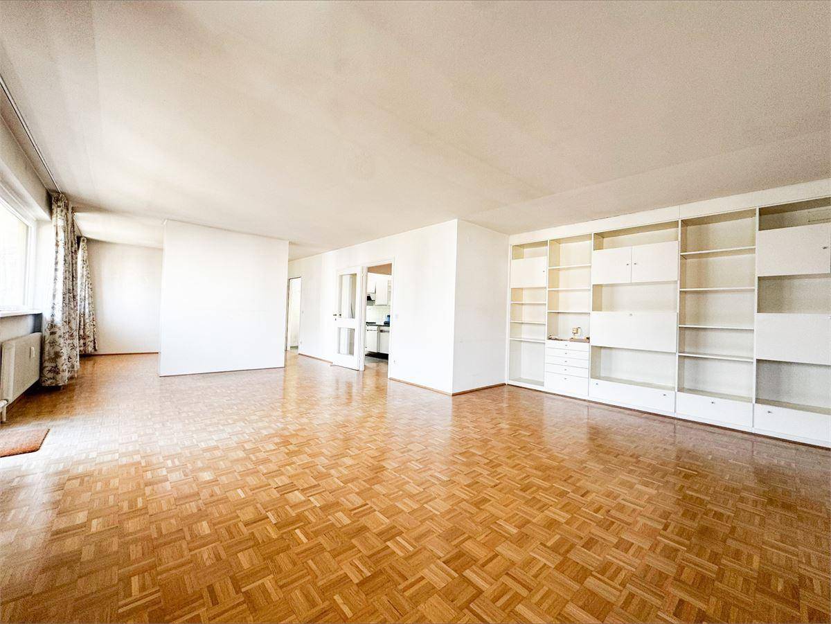 Geräumiges Wohnzimmer mit Fischgrätparkettboden und eingebauten weißen Regalen, bereit zur individuellen Gestaltung.