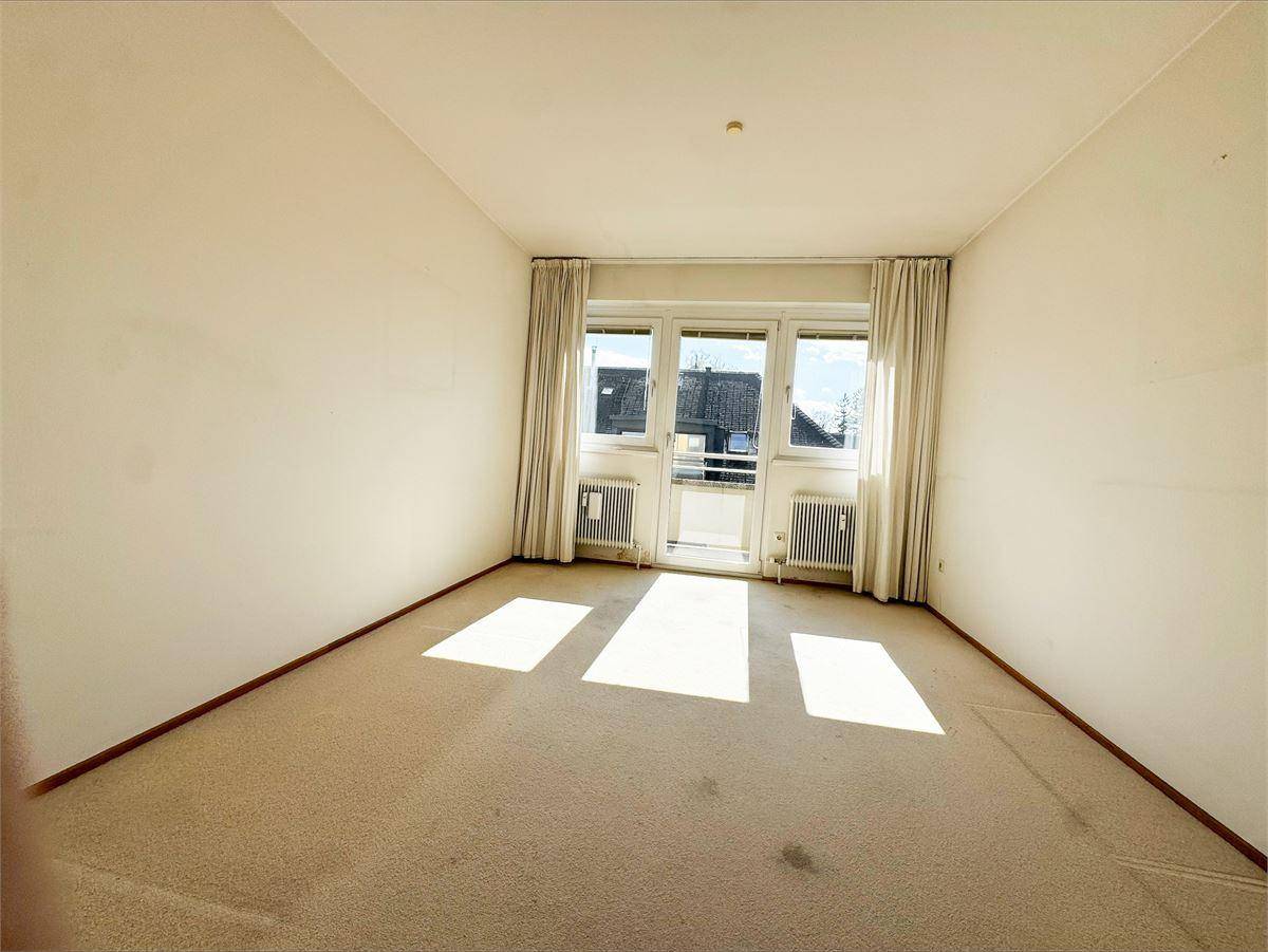 Lichtdurchflutetes Schlafzimmer mit Teppichboden und breitem Fenster mit Balkonzugang.