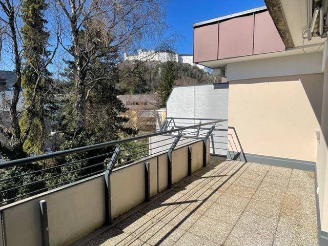 Heller Balkon mit Fliesenboden und weitem Blick auf die Stadt und die umliegende Natur.