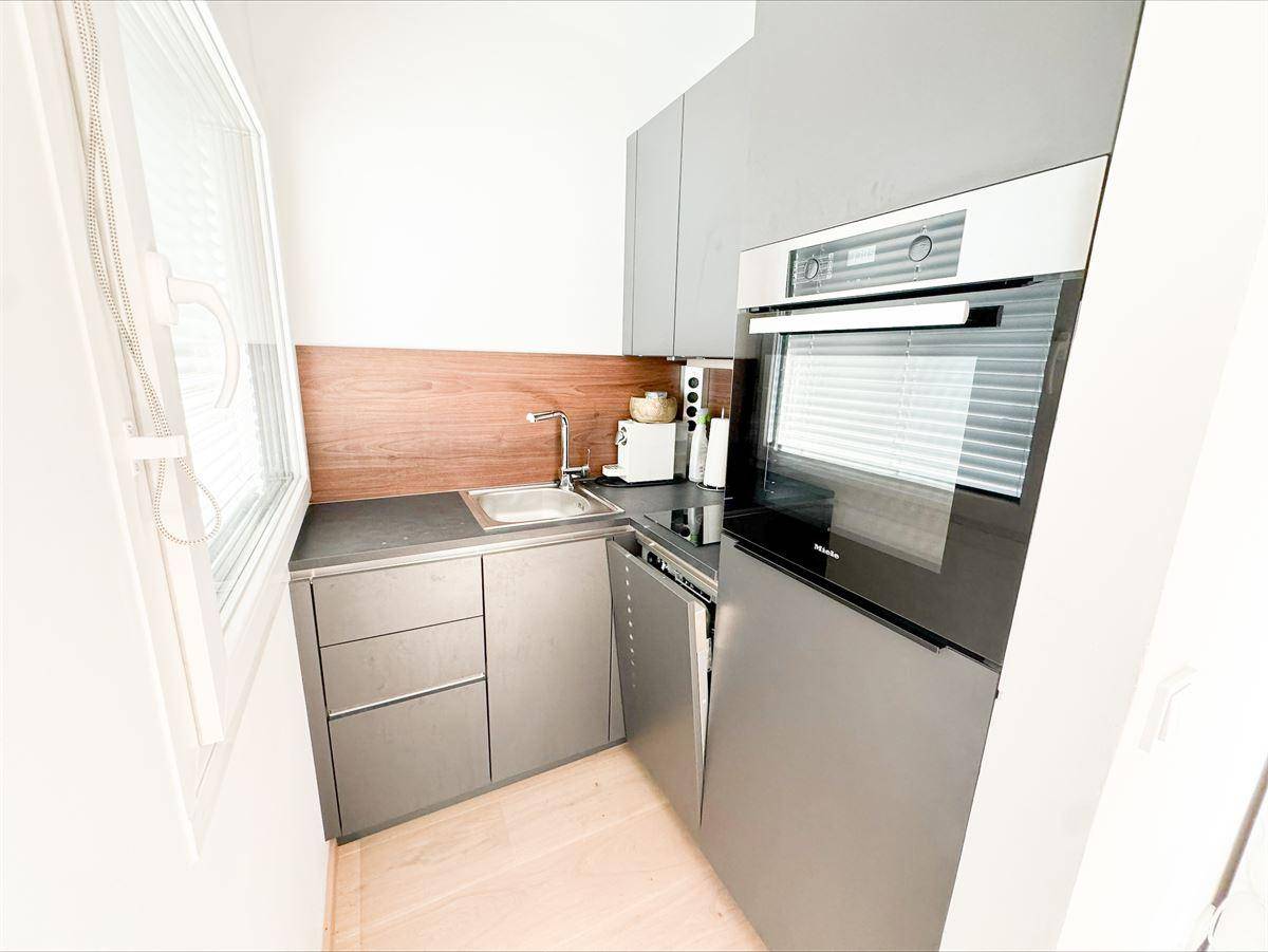 Moderne Küchenzeile mit grauen Schränken, integrierten Geräten und einem Fenster.