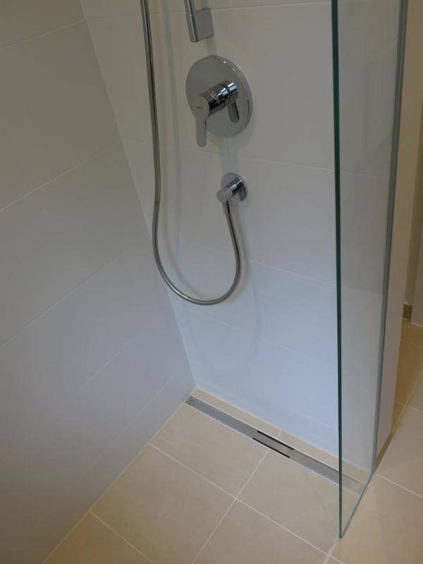 Bodengleiche Dusche mit Glasabtrennung und modernen Fliesen im Badezimmer.