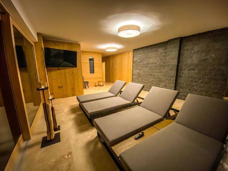 Entspannungsraum mit Holzverkleidung und Steinwand, ausgestattet mit bequemen Liegen und indirekter Beleuchtung.