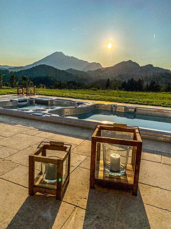 Detailansicht der Terrasse mit dekorativen Laternen neben dem Pool und Whirlpool, mit malerischem Bergblick.