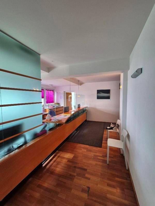 Empfangsbereich mit Holzfußboden, langer Theke und moderner Glasabtrennung.
