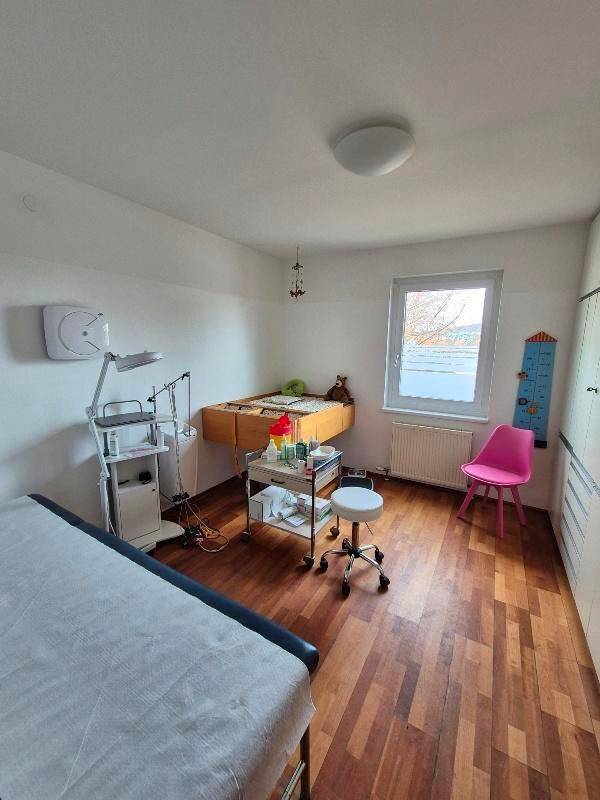 Behandlungszimmer mit Untersuchungsliege, medizinischem Gerät und Fenster.
