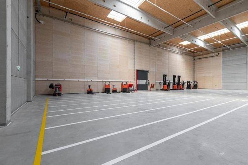 Große, leere Lagerhalle mit hohen Decken, Betonboden und Oberlichtern, bereit für den Betrieb.