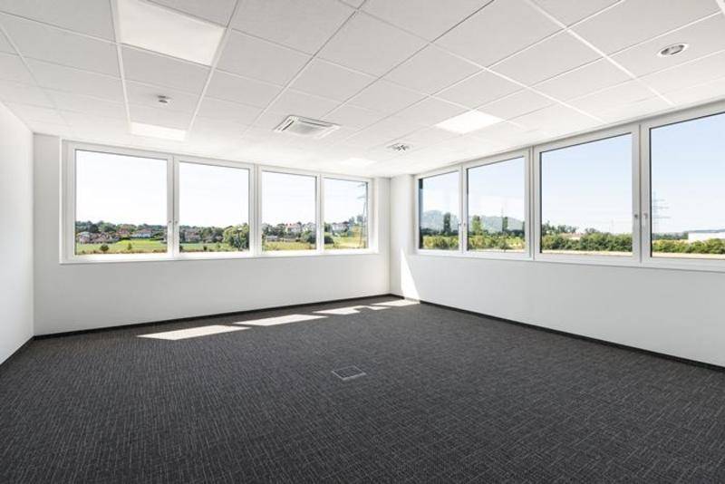Helles, leeres Büro mit großen Fenstern, die viel Tageslicht hereinlassen und einen weiten Ausblick bieten.