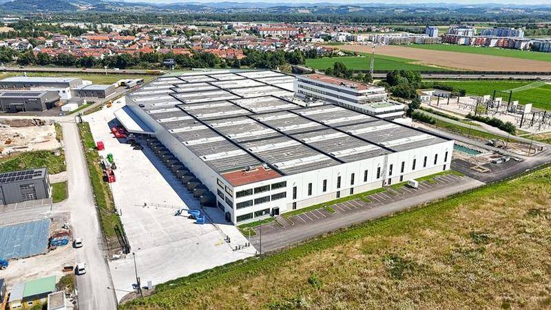 Luftaufnahme eines großen modernen Industrie- und Bürokomplexes mit weitläufigen Parkplätzen und Grünflächen.