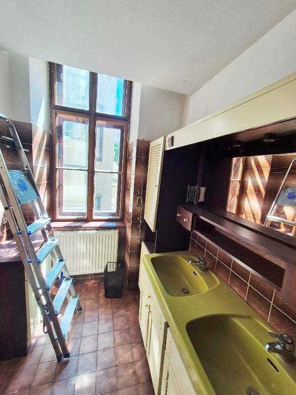 Badezimmer mit olivgrünem Doppelwaschbecken, braunen Fliesen und Fenster.