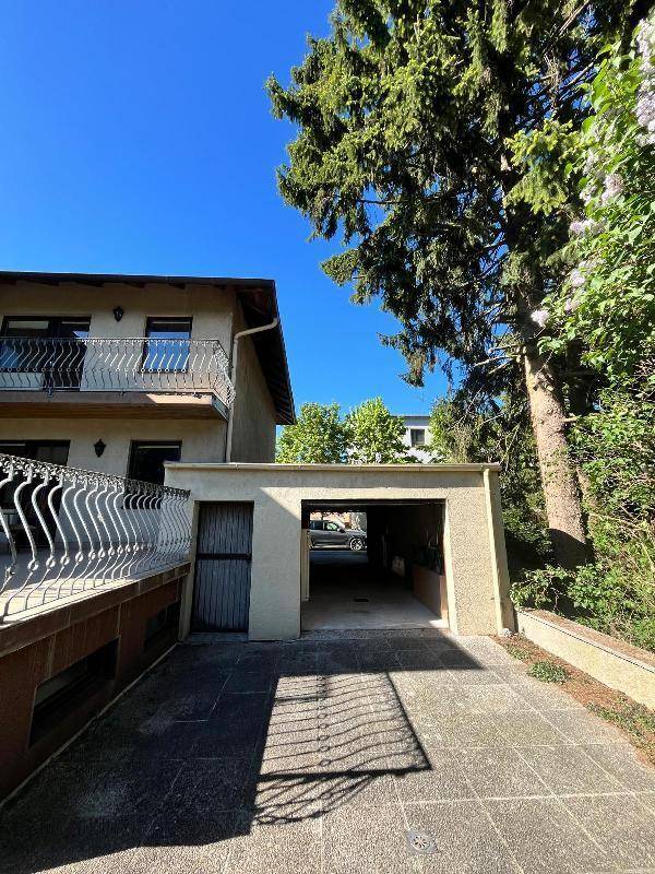Zufahrt zum Carport und zur Garage, umgeben von Bäumen.