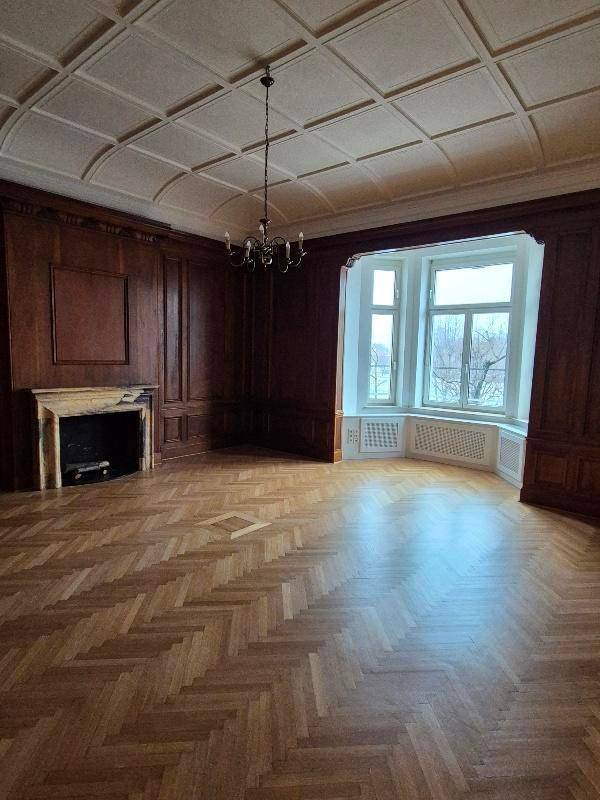 Elegantes Wohnzimmer mit Fischgrätparkett, dunkler Holzvertäfelung, Kamin und großem Erkerfenster.
