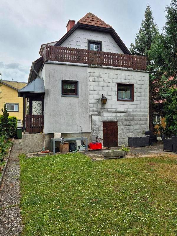 Rückseite des Hauses mit kleinem Gartenbereich und einem Balkon im Obergeschoss.
