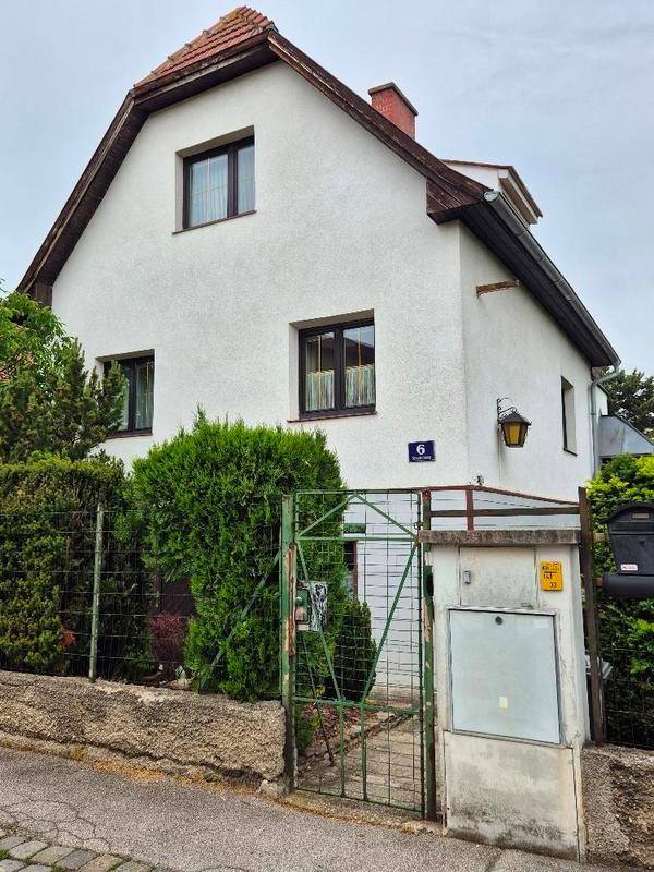 Vorderansicht des Hauses mit Eingangstor und gepflegter Hecke.