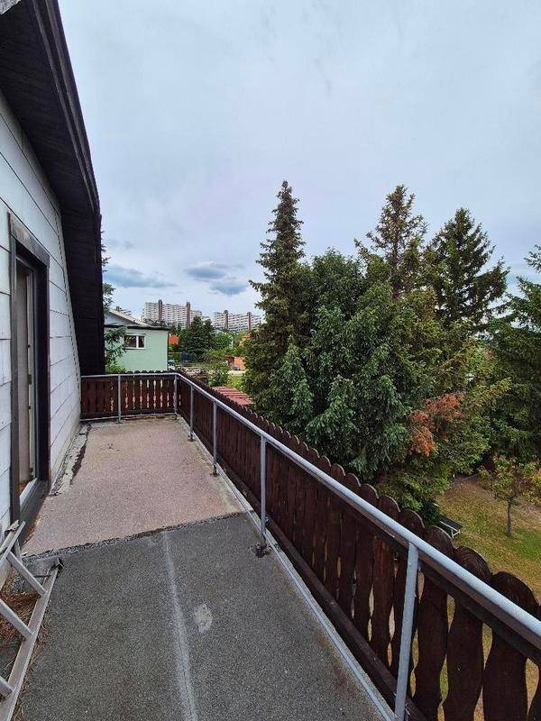 Langer Balkon mit Holzgeländer und Blick auf die umliegende Wohngegend.