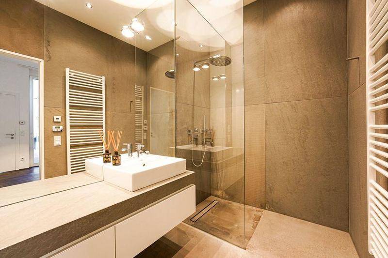 Modernes Badezimmer mit großformatigen Fliesen, einer begehbaren Dusche und einem beheizten Handtuchhalter.
