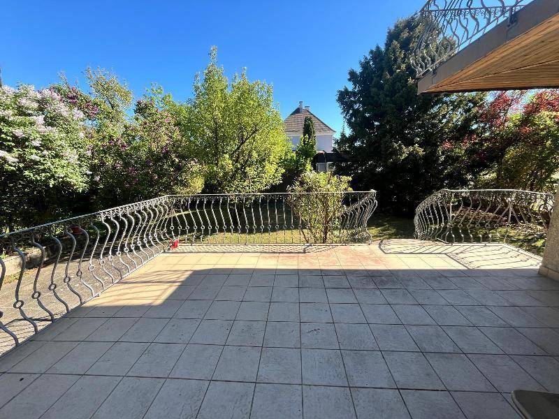 Geräumige Terrasse mit schmiedeeisernem Geländer und Blick in den grünen Garten.
