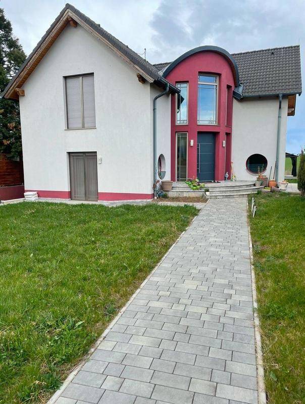 Attraktive Hausfassade mit rotem Akzent und gepflastertem Zugangsweg.