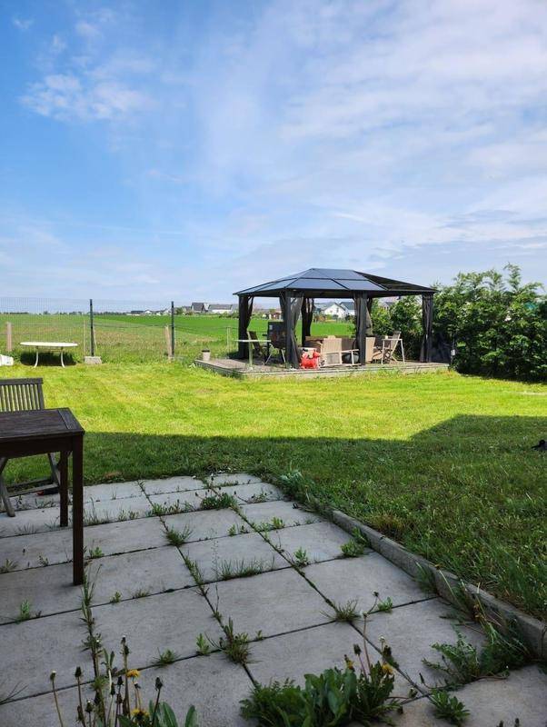 Terrasse mit Blick auf den weitläufigen Rasen, einen Pavillon und die umliegende Landschaft.