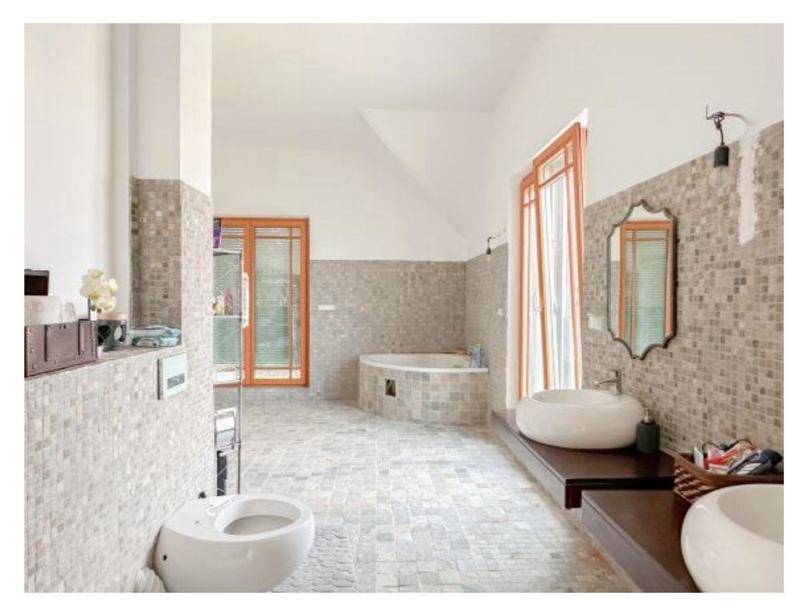 Modernes Badezimmer mit Mosaikfliesen, zwei Waschbecken und einer Eckbadewanne.