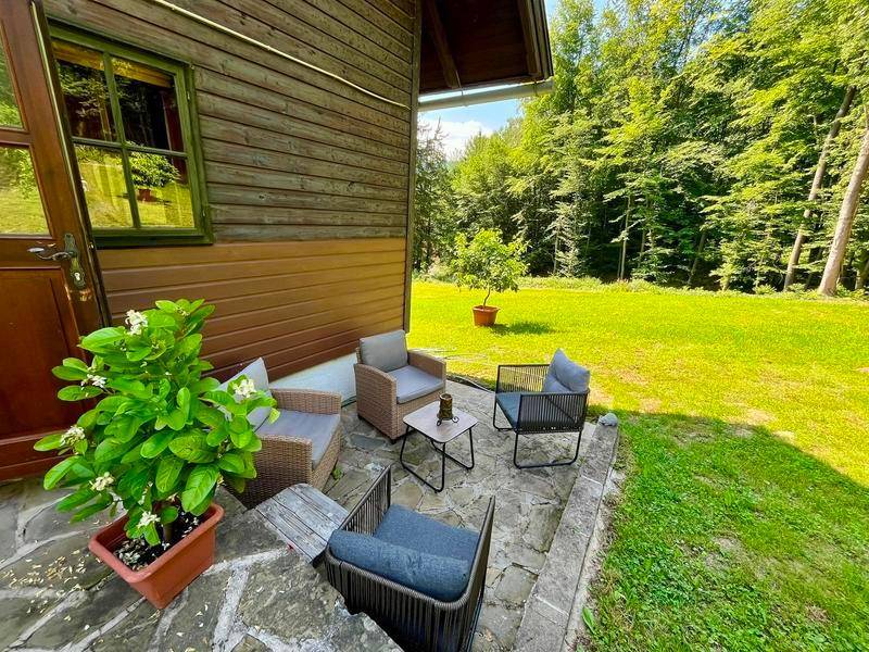 Gemütliche Terrasse mit Sitzgelegenheiten und Blick ins Grüne am Waldrand.