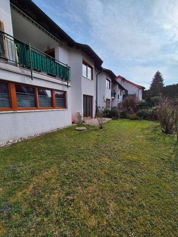 Gepflegter Gartenbereich vor einem Mehrfamilienhaus mit Balkonen und grüner Umgebung.