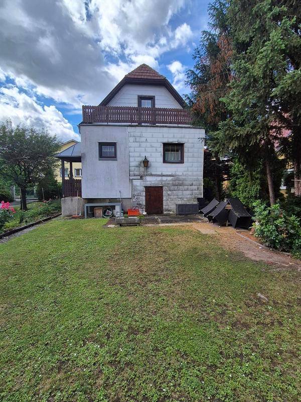 Rückansicht eines Hauses mit Balkon im Obergeschoss und einem weitläufigen Gartenbereich.