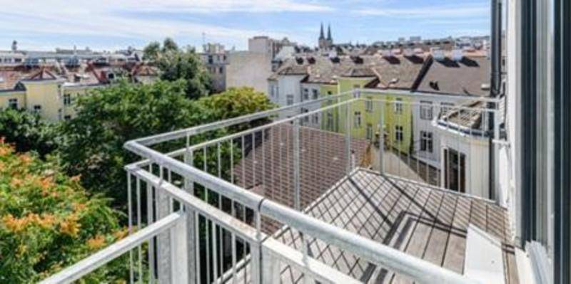 Balkon mit Holzboden und Metallgeländer bietet einen weiten Blick über die Dächer der Stadt.