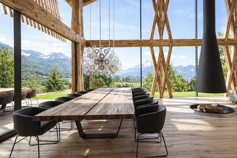Eleganter Essbereich mit großem Holztisch, modernen Stühlen und atemberaubendem Bergblick durch Panoramafenster.