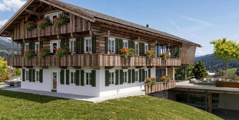 Traditionelles Alpenhaus mit Holzbalkonen, grünen Fensterläden und Blumenkästen in sonniger Hanglage.
