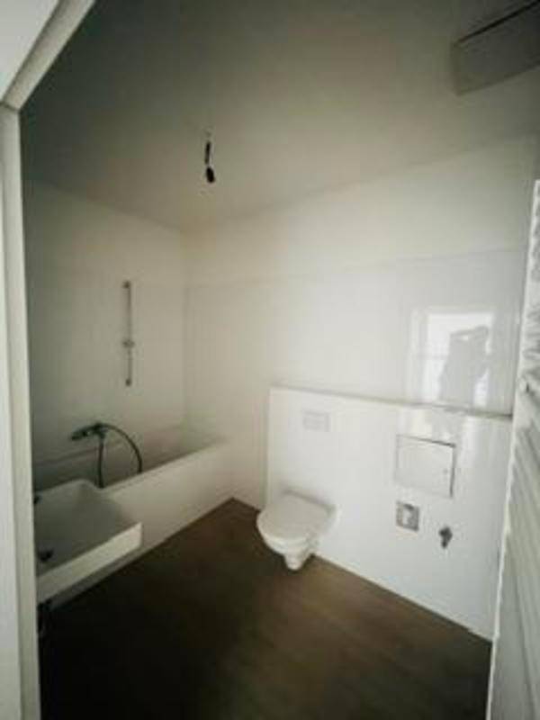 Modernes Badezimmer mit Badewanne, Toilette und hellem Boden.