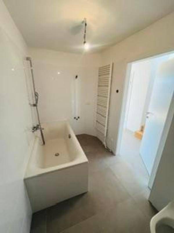 Modernes Badezimmer mit Badewanne, Duschvorrichtung und beheiztem Handtuchhalter.