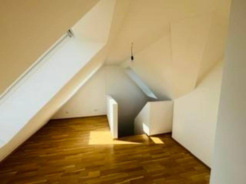 Geräumiger Dachbodenraum mit Holzboden, Dachfenster und Zugang zu einer Treppe.