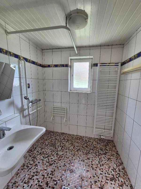 Modernisiertes Badezimmer mit Mosaikfliesen, Dusche und beheiztem Handtuchhalter.