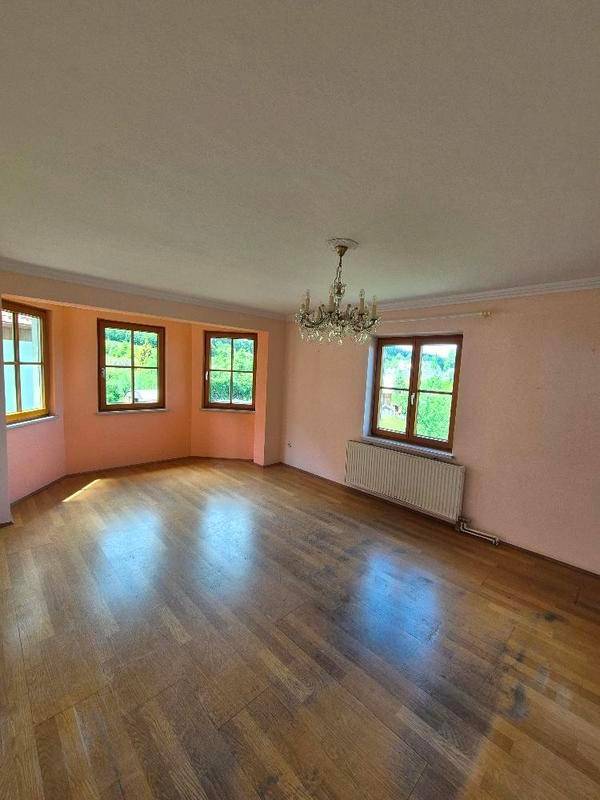 Geräumiges Wohnzimmer mit Parkettboden, rosa Wänden und Kronleuchter.