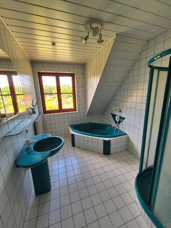 Badezimmer mit blauer Eckbadewanne, Dusche und Dachschräge.