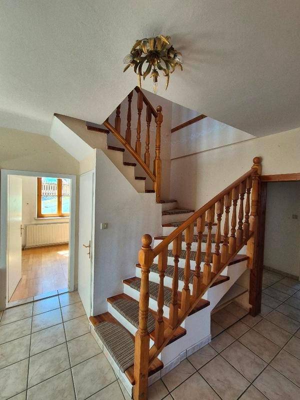 Eingangsbereich mit Holztreppe, Fliesenboden und dekorativer Deckenleuchte.
