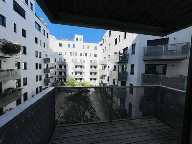 Balkon mit Blick auf den begrünten Innenhof, umgeben von modernen Wohngebäuden.