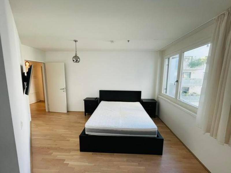 Helles Schlafzimmer mit Parkettboden, Doppelbett und großen Fenstern für viel Tageslicht.
