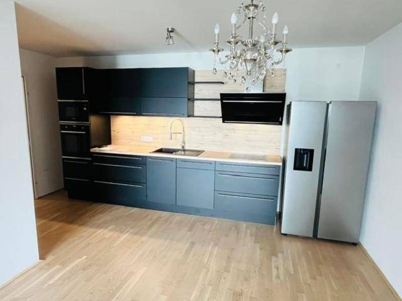 Moderne Küche mit dunklen Schränken, Holzarbeitsplatte und hochwertigen Einbaugeräten.