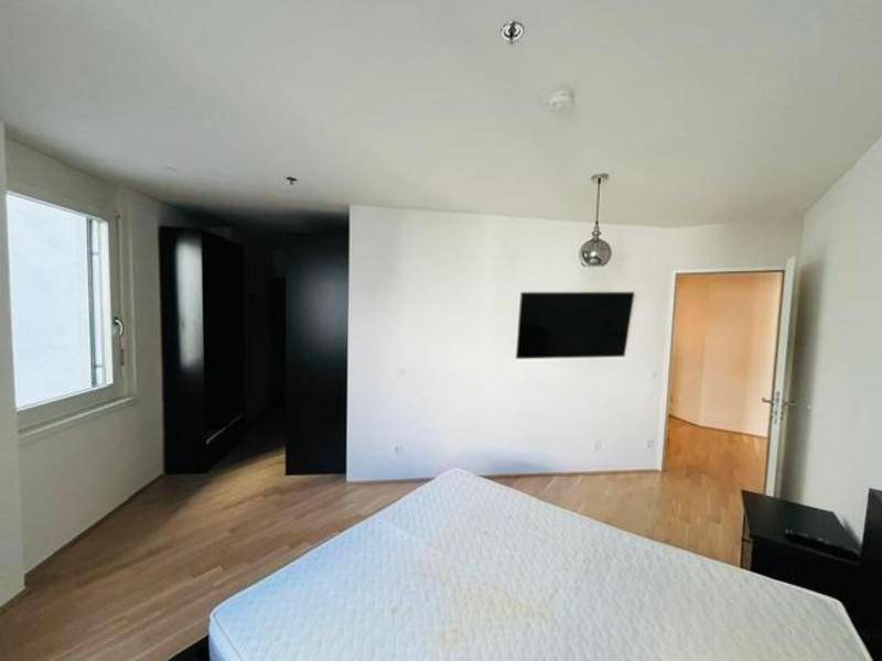 Schlafzimmer mit Parkettboden, Wandfernseher und integrierten dunklen Kleiderschränken.