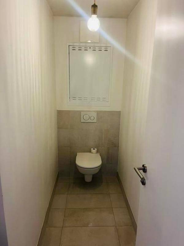 Separates WC mit Wand-WC, grauen Fliesen und minimalistischem Design.