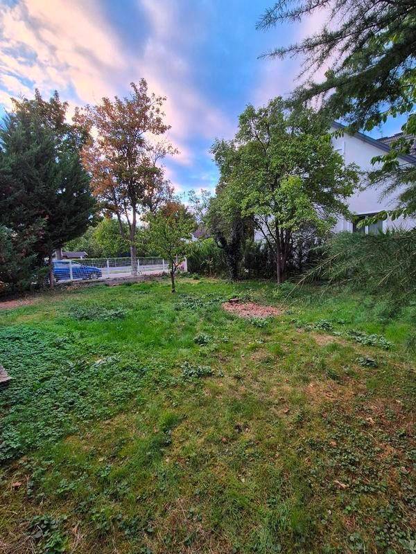 Weitläufiger Gartenbereich mit Rasen, Bäumen und Blick auf die Umgebung.