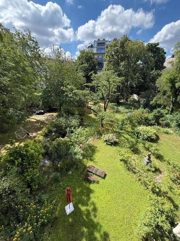 Weitläufiger grüner Garten mit Liegestühlen und einem modernen Gebäude im Hintergrund.