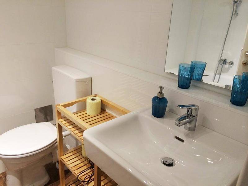 Helles Badezimmer mit weißer Einrichtung, Waschbecken, Toilette und einem großen Spiegel.