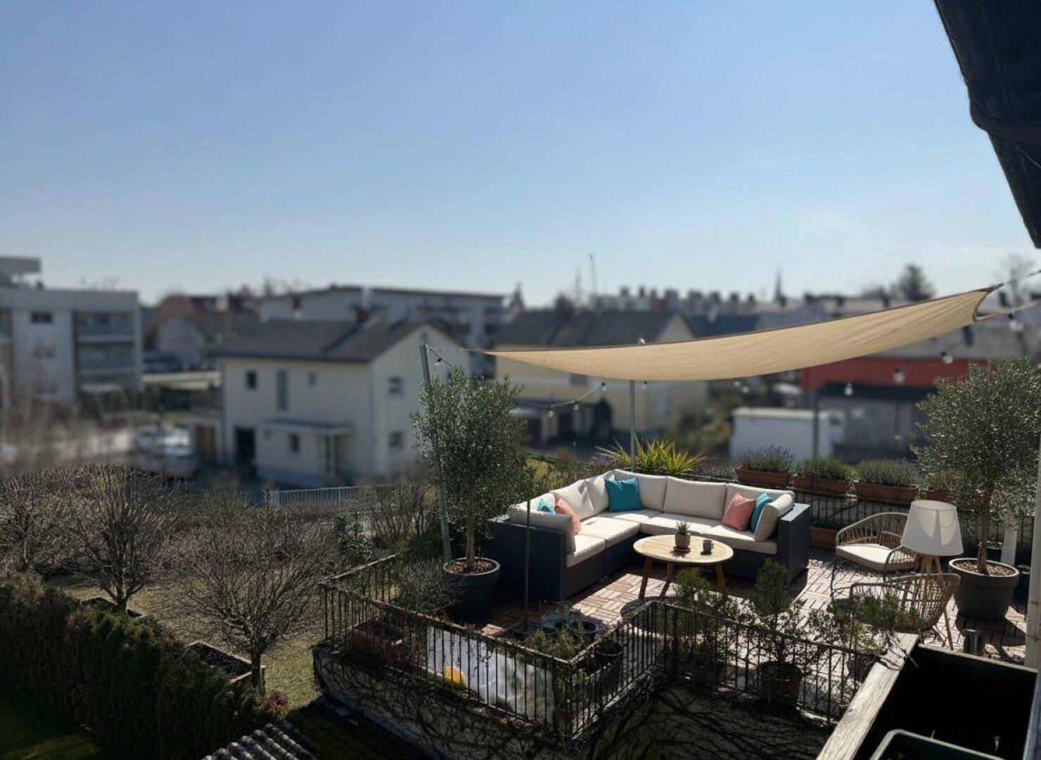 Möblierte Dachterrasse mit gemütlicher Sitzecke und Sonnensegel, bietet einen weiten Blick über die Umgebung.
