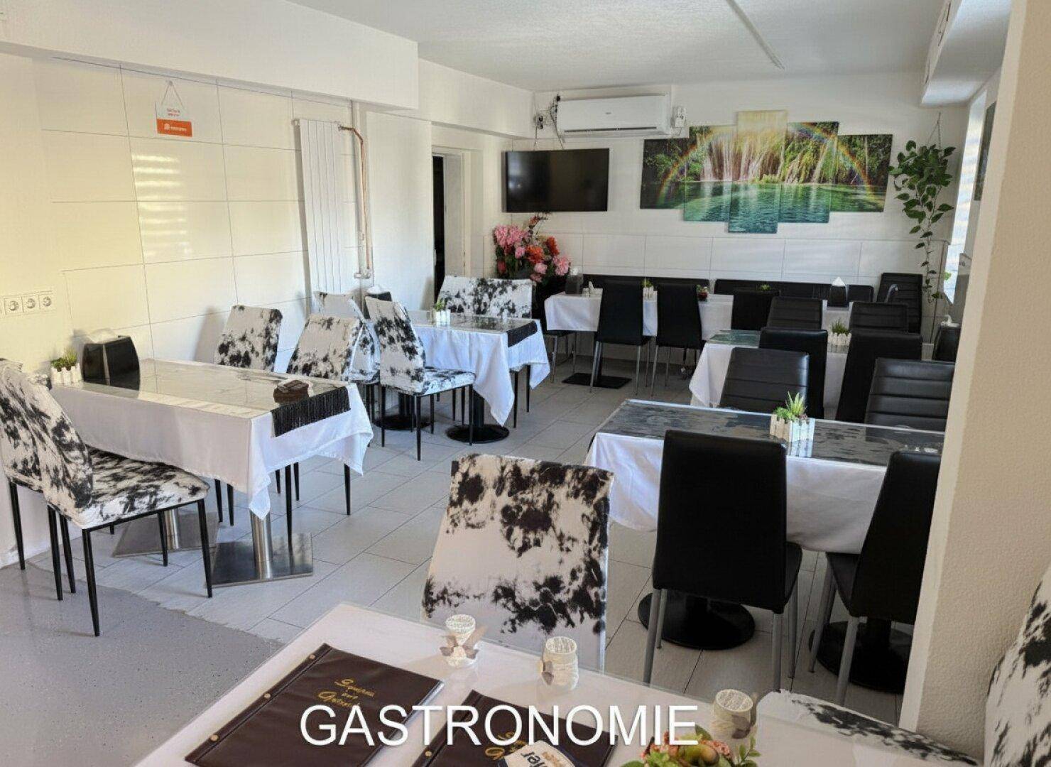 Gastronomiebereich mit Tischen und Stühlen, dekoriert mit modernen Bildern und Klimaanlage.